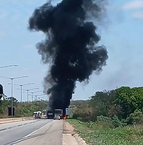Carreta pega fogo após colisão e carga de adubo fica espalhada na pista