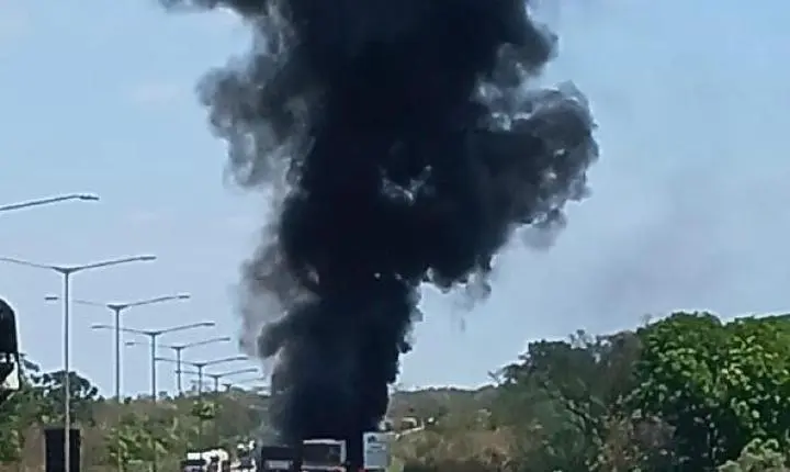 Carreta pega fogo após colisão e carga de adubo fica espalhada na pista